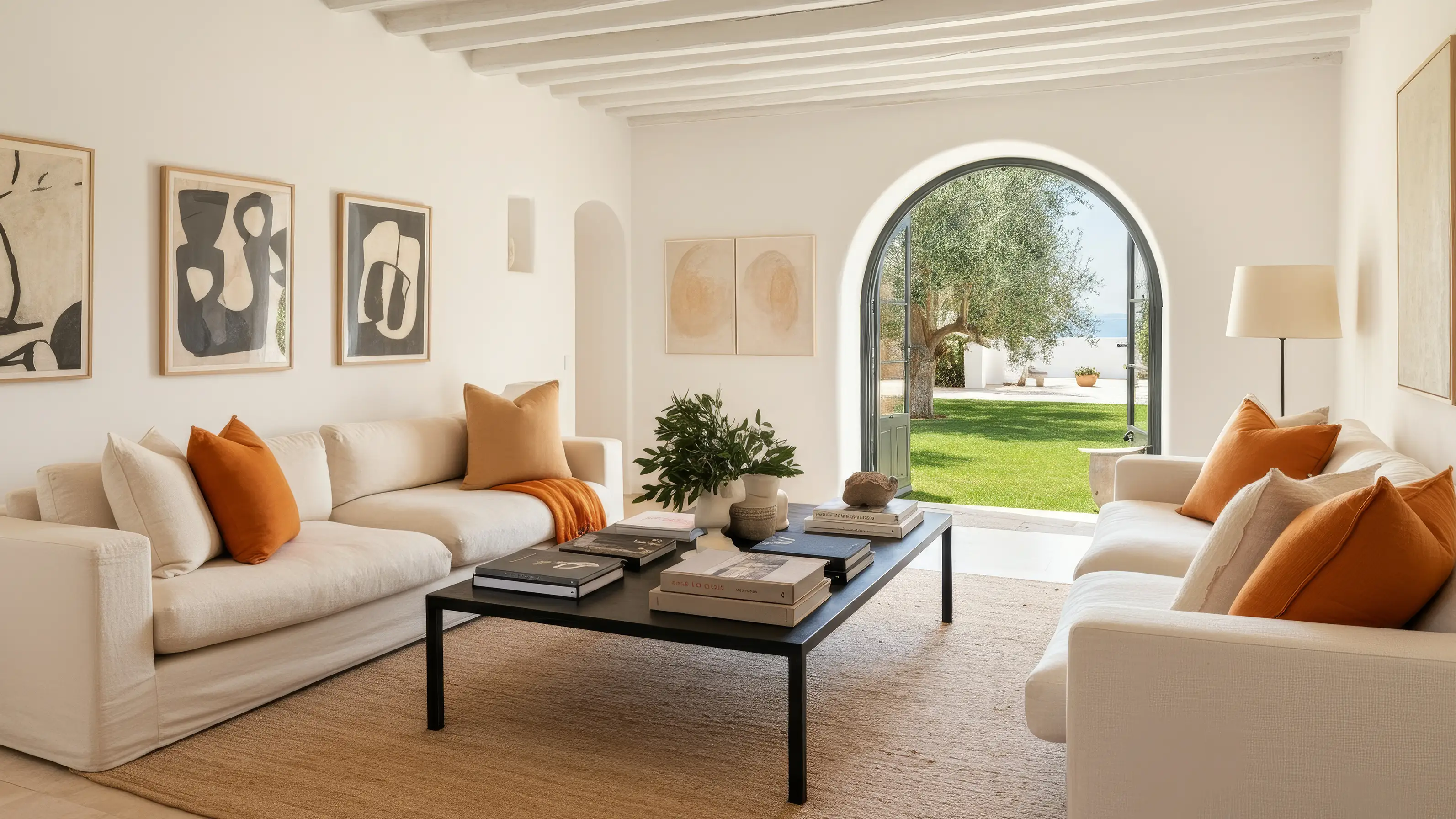 Living room with cream sofas, orange cushions and an arched door onto the garden