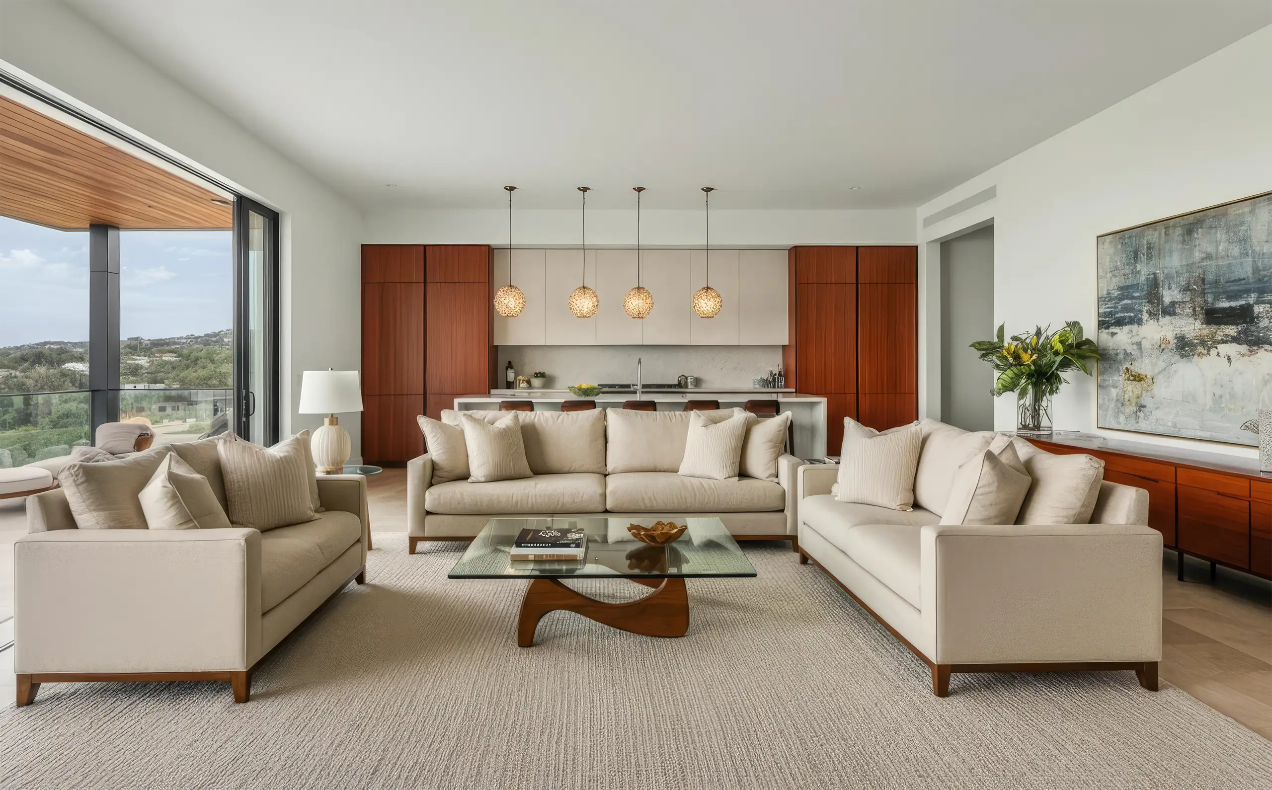 Open living room with cream sofas, a glass coffee table and a wood-panelled kitchen