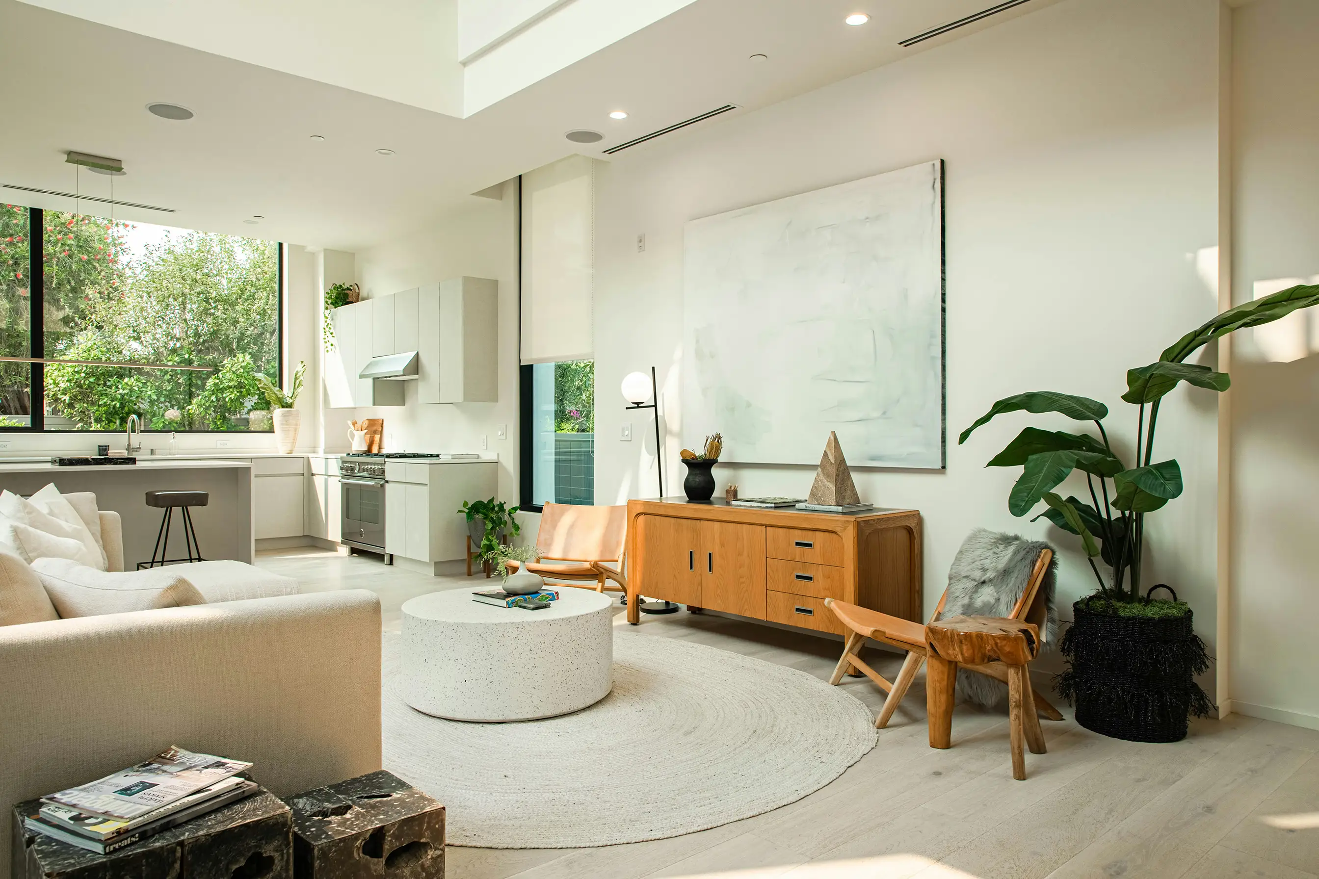 Bright living room with a white sofa, a round coffee table and a wooden sideboard