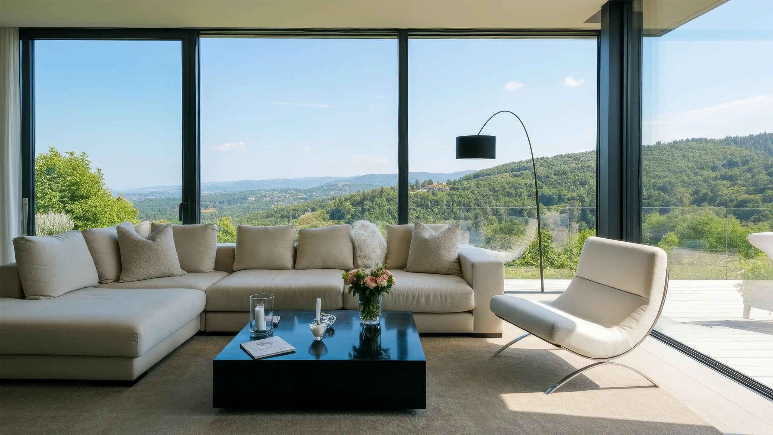 Living room with a large cream sectional and floor-to-ceiling windows onto wooded hills